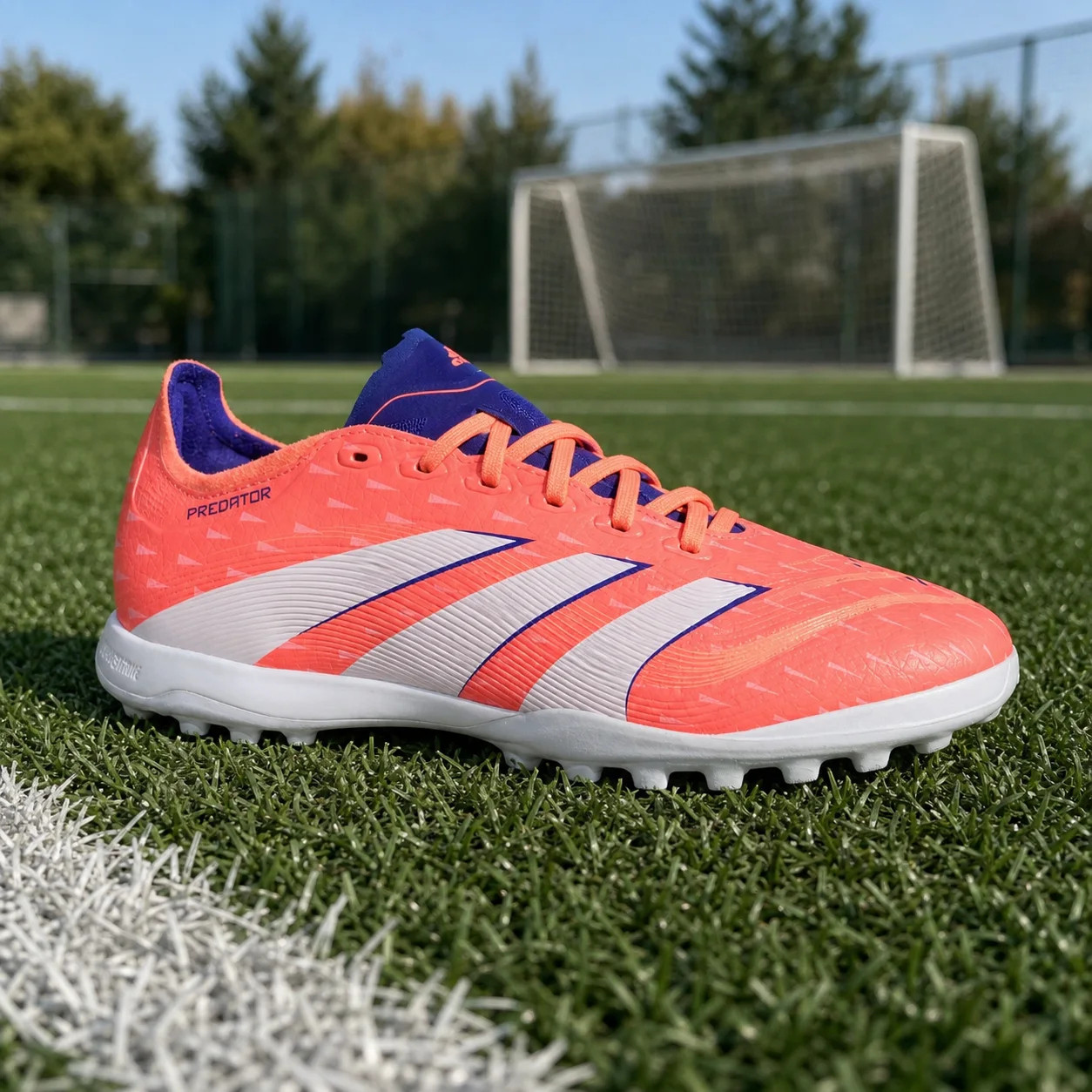 Foto da chuteira society adidas Predator League coral sobre gramado
